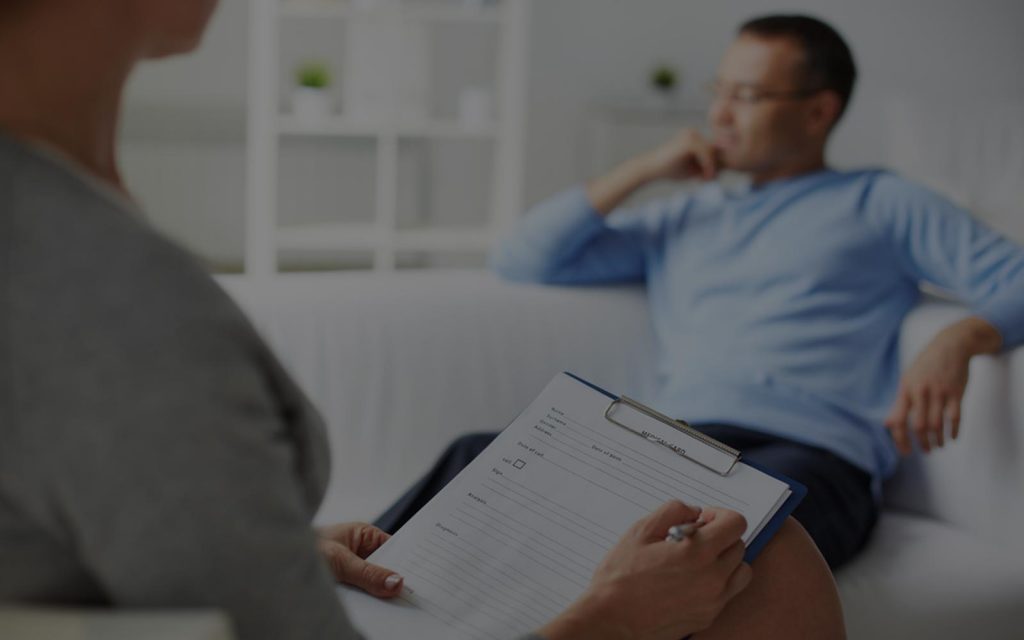A client talks while a therapist takes notes on a clipboard
